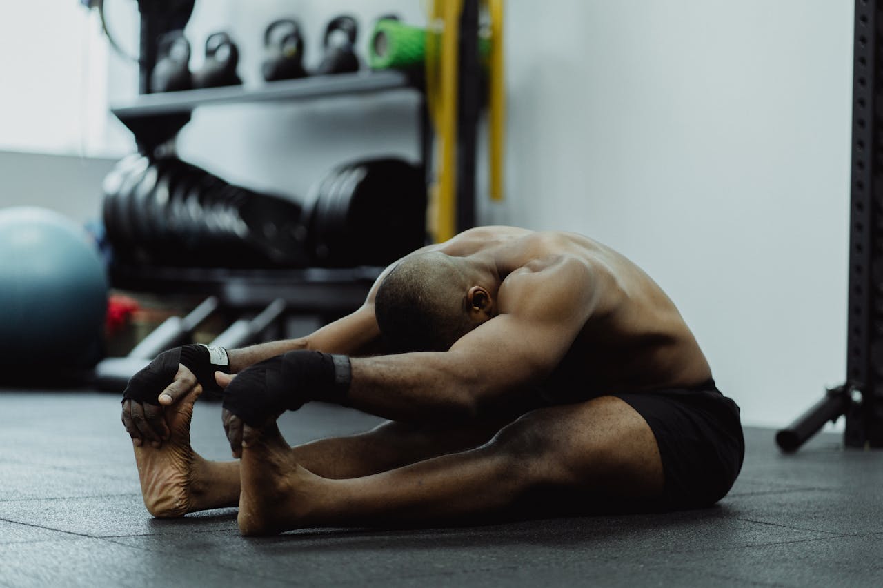 Man doing seated stretch in gym, emphasizing fitness and flexibility training.